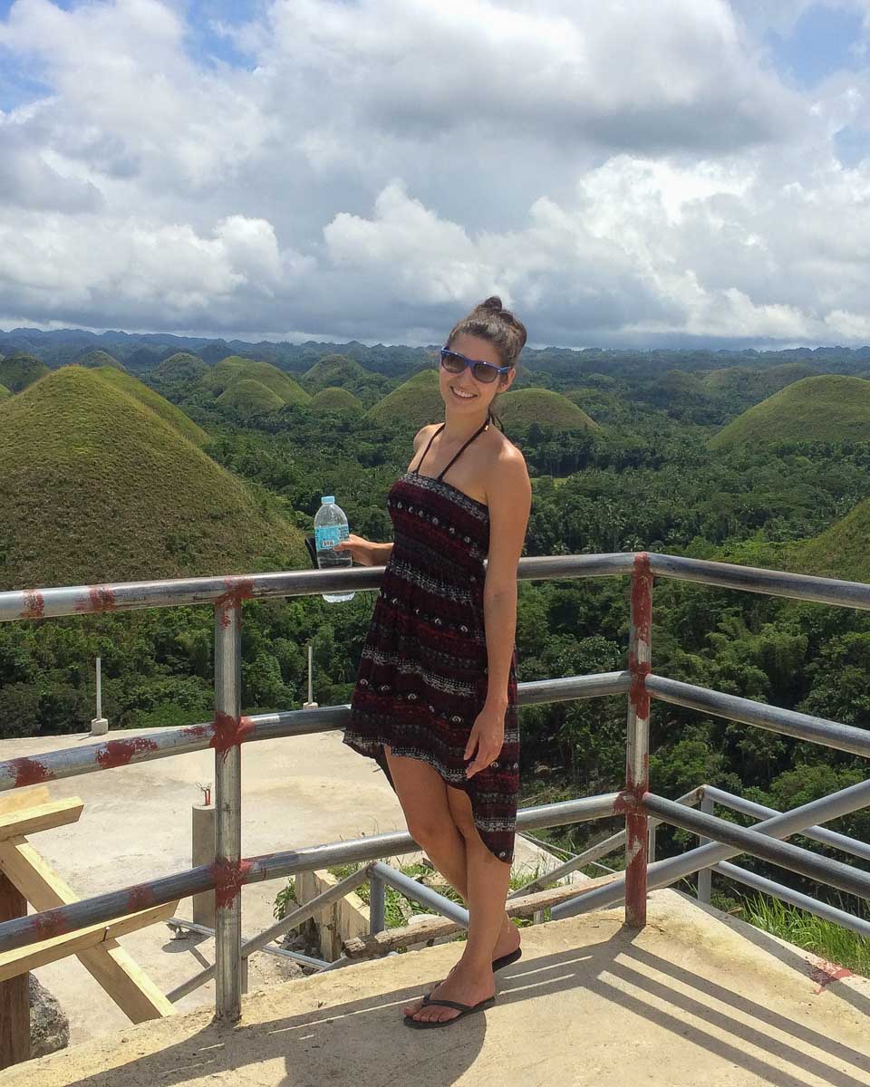 A-woman-smiles-at-the-chocolate-hills-in-bohol-Philippines
