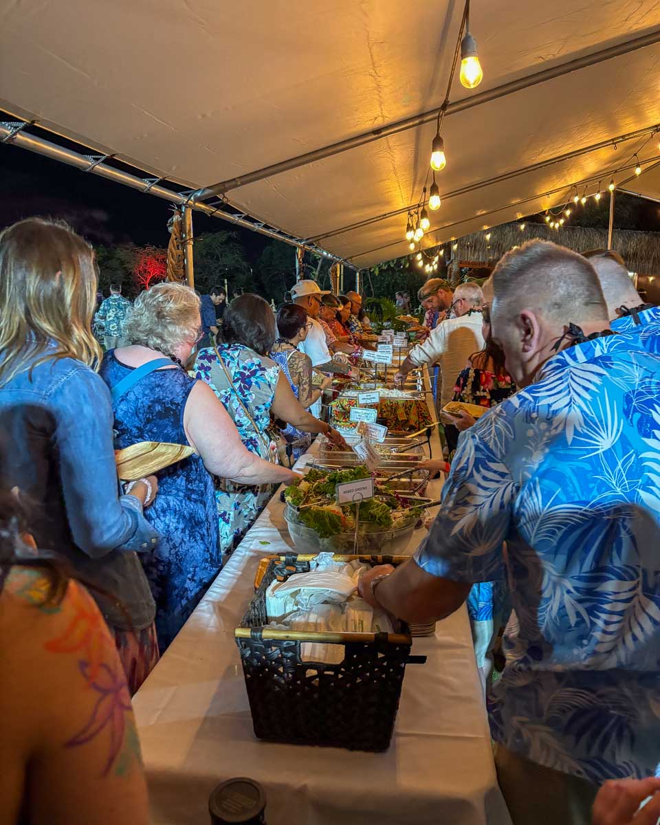 People grab food at a buffet during a luau on Oahu Hawaii